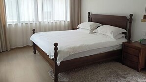 A bedroom with a wooden bed, white bedding, a nightstand, a lamp, and a window with curtains. - Yandang Mountain Sulv Homestay (Yueqing)