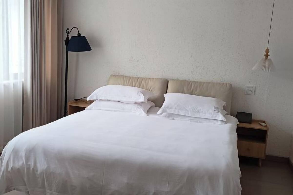 A hotel room with a bed, bedside tables, a lamp, and a nightstand.