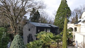 Una casa moderna de exterior oscuro, rodeada de diversos árboles y plantas.