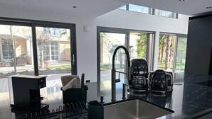 Una cocina moderna con encimera negra, lavaplatos integrado y cafetera.