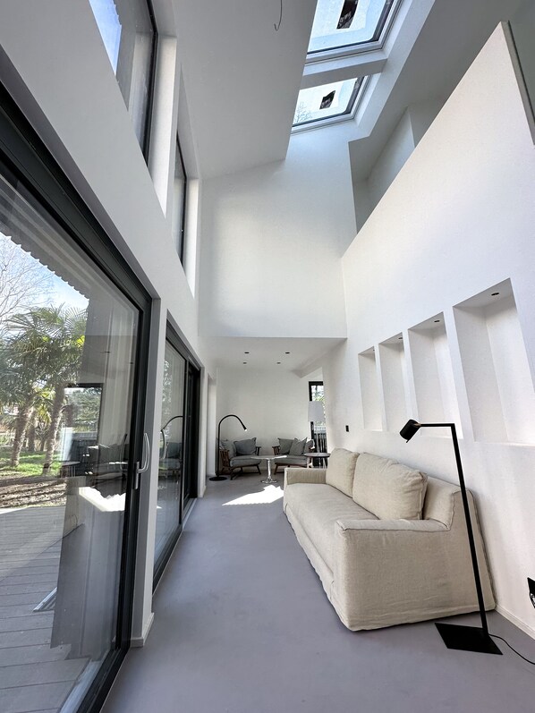 Un intérieur moderne avec un canapé, une table et des chaises, un lampadaire et des fenêtres de toit.