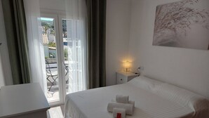 A hotel room with a bed, a bedside table with a lamp, a window with curtains, and a view of the outside balcony. - Villa ideally located 10 minutes from the beach (L'Escala)