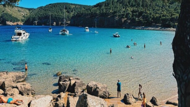 A coastal scene with clear turquoise water, rocky shoreline, and boats. - Villa ideally located 10 minutes from the beach (L'Escala)