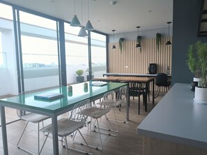 Ein moderner Arbeitsbereich mit Glastisch, weißen Stühlen und Pendelleuchten.