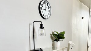 A white desk with a clock, a lamp, and a plant. - Tower Grove Pet Friendly 2nd Floor Studio - 4 mi to SLU & Barnes -Shared Laundry (St. Louis)