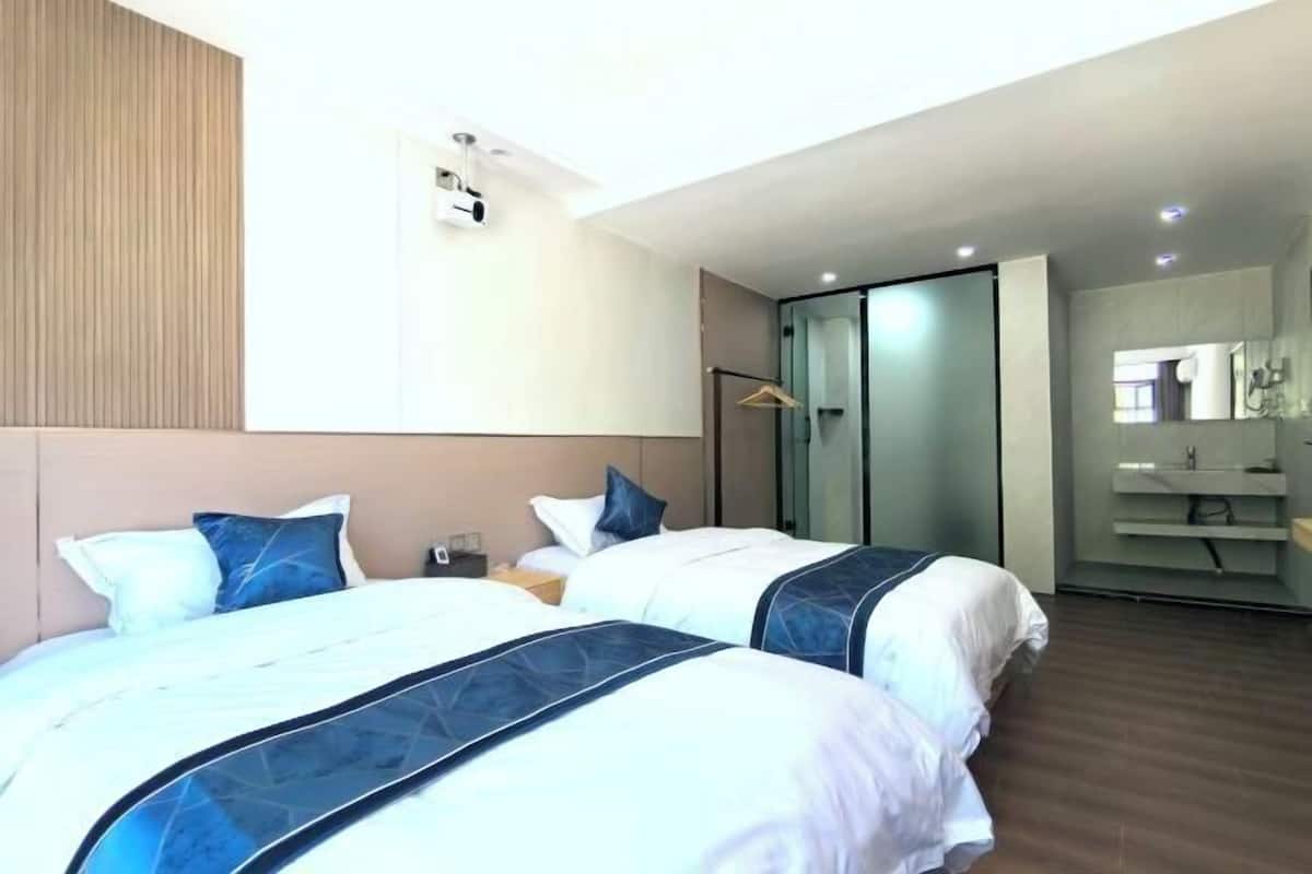 A hotel room with two beds, a sliding door to a bathroom, and a modern design.