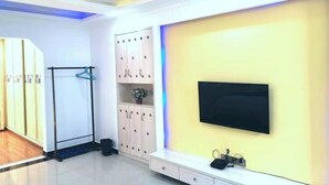 A room with a TV mounted on the wall, a wardrobe, a coat rack, and a bench. - Lubianbian Inn (Zhangjiajie)