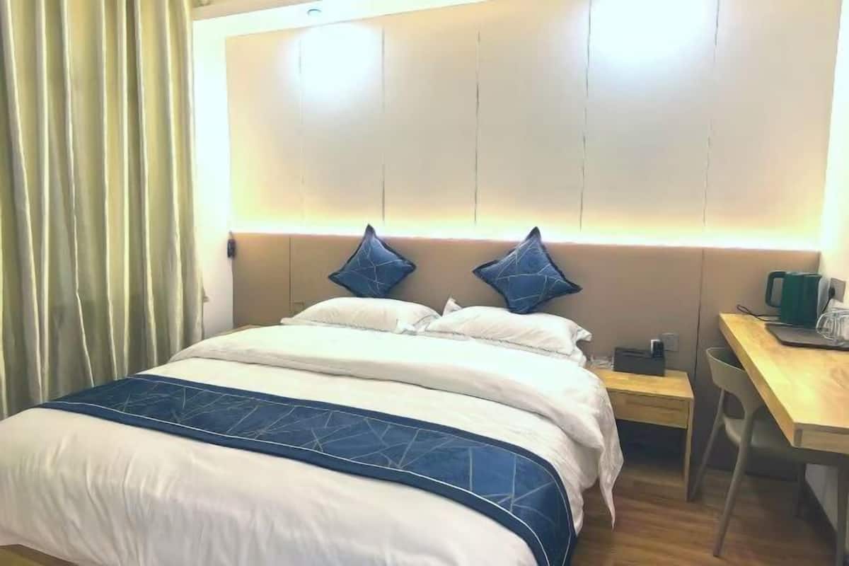 A hotel room with a bed, a desk, and a chair.