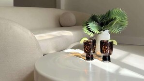 A modern living room with a round white coffee table, a sofa, and a potted plant. - Mr. Nomad: Casa Bohem in Uptown (Dallas)