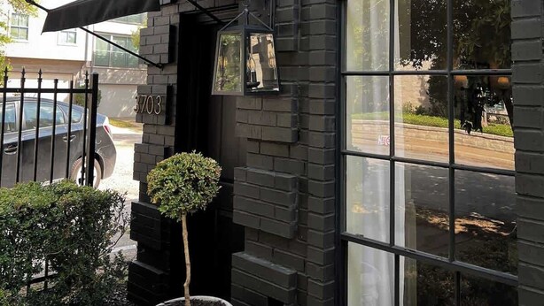 A building with a brick facade, a large arched window, and a small potted plant. - Mr. Nomad: Casa Bohem in Uptown (Dallas)
