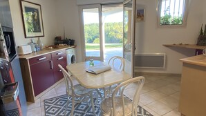 A compact kitchen with a dining area, a washing machine, and a large window offering a view of greenery. - Accomodation, bed and breakfast, equestrian reception Chemin de St Jacques Flamarens Gers (Flamarens)