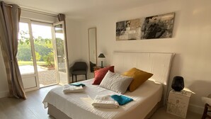 A neatly made bed with pillows and folded towels, a bedside table with a lamp, and a view through a sliding glass door to an outdoor area. - Accomodation, bed and breakfast, equestrian reception Chemin de St Jacques Flamarens Gers (Flamarens)