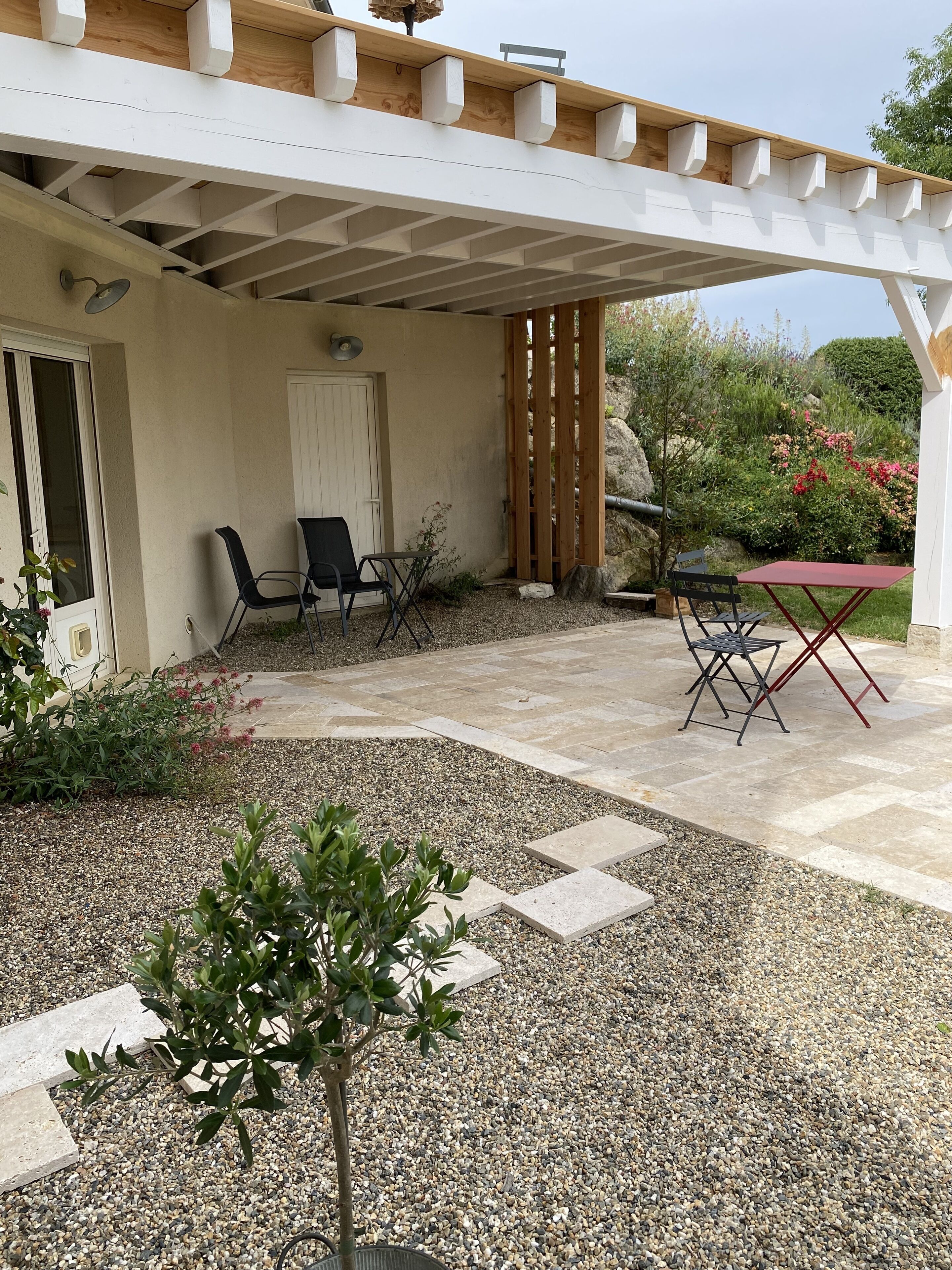Un patio couvert aménagé avec des sièges, une petite table et une porte.