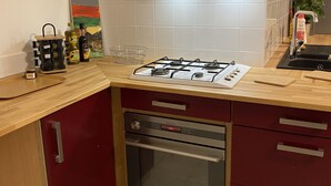 A kitchen with a gas stove, oven, and a sink. There is a small cabinet with a handle, a bottle of dish soap, and a jar on the counter. - Accomodation, bed and breakfast, equestrian reception Chemin de St Jacques Flamarens Gers (Flamarens)