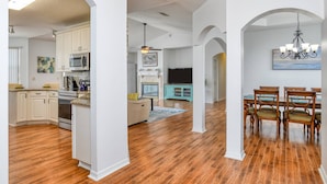 A spacious kitchen with white cabinets, a microwave, and a stove. There is a dining area with a wooden table and chairs. - Sea Glass House (St. Augustine)