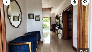 Un pasillo con sillones tapizados en azul, diplomas enmarcados en la pared y vistas a una zona de piscina.