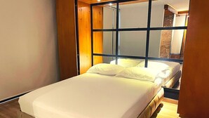 A bedroom with a bed, wooden floor, and a large window. - Apto Calle 76 x5 by Caribecheap (Barranquilla)