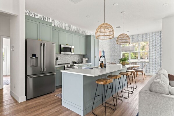 Enjoy cooking in this kitchen with a central island, bar stools, and stainless steel appliances.