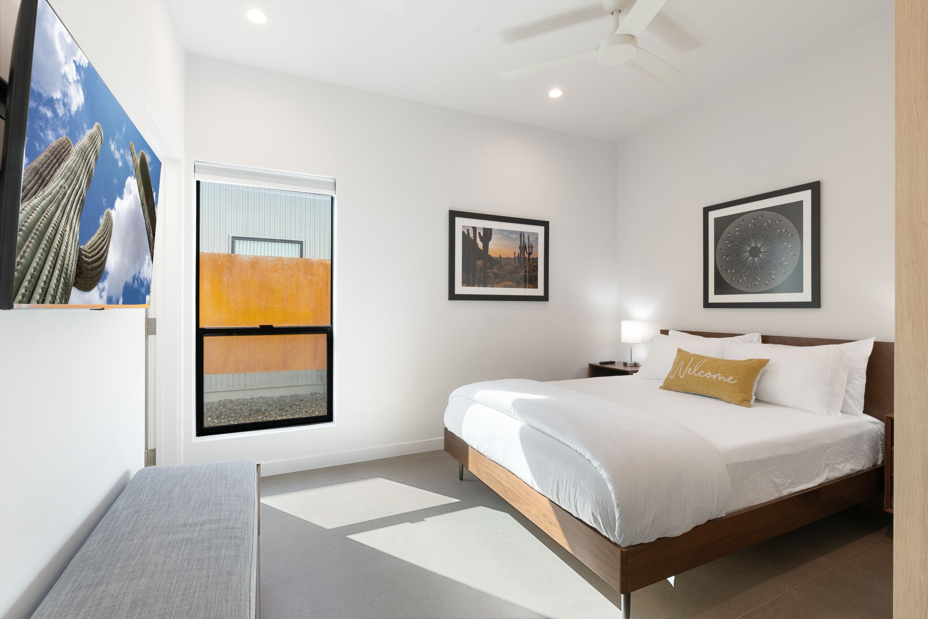 Une chambre d’hôtel moderne avec un grand lit, une table de chevet avec une lampe et une fenêtre donnant sur le désert.