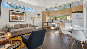 A modern living room with a sofa, a coffee table, and a dining area with a table and chairs. - 4Square Complex (Phoenix)