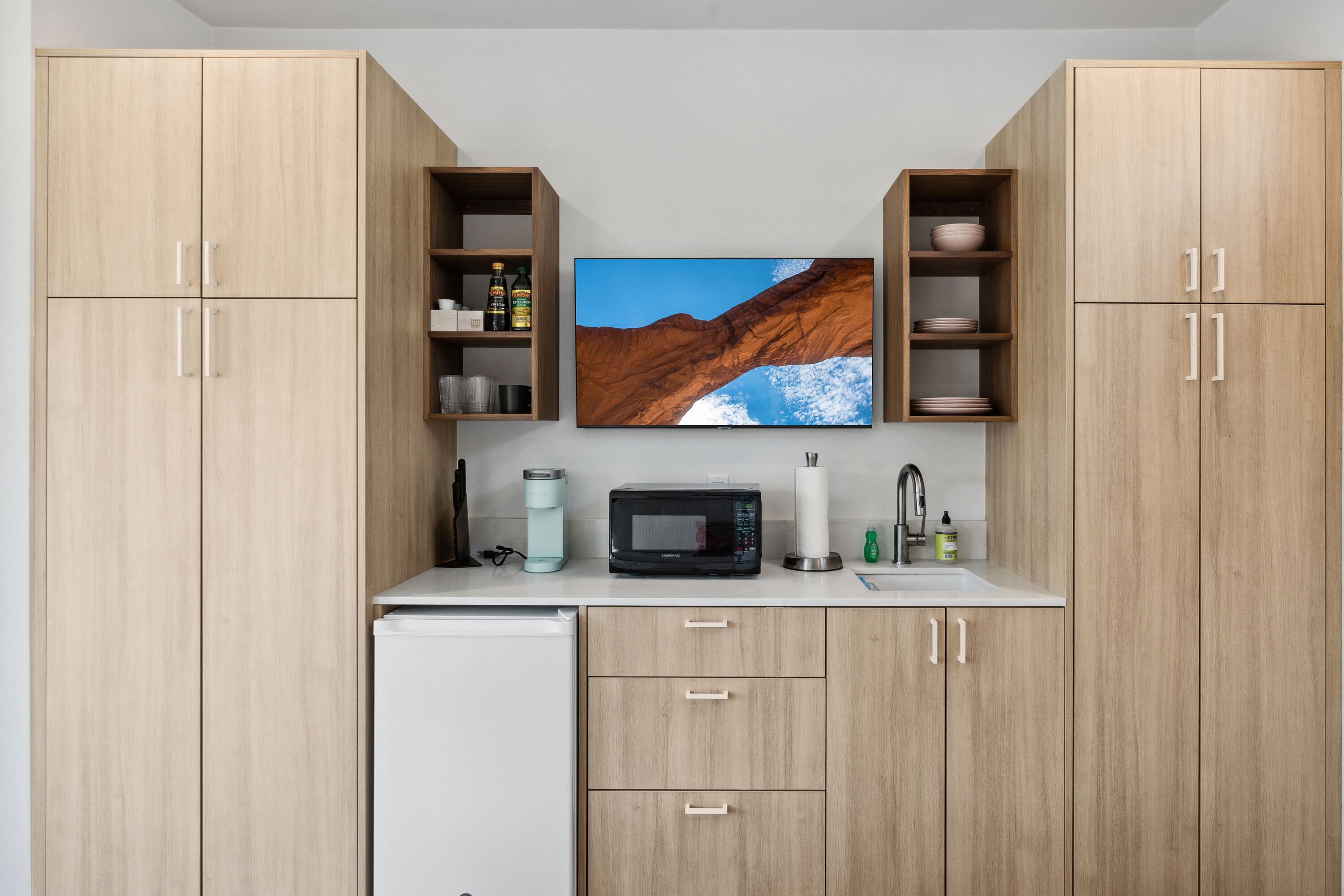 Une cuisine dotée de meubles en bois, d’un four à micro-ondes, d’un évier et d’une grande fenêtre offrant une vue sur un paysage montagneux.