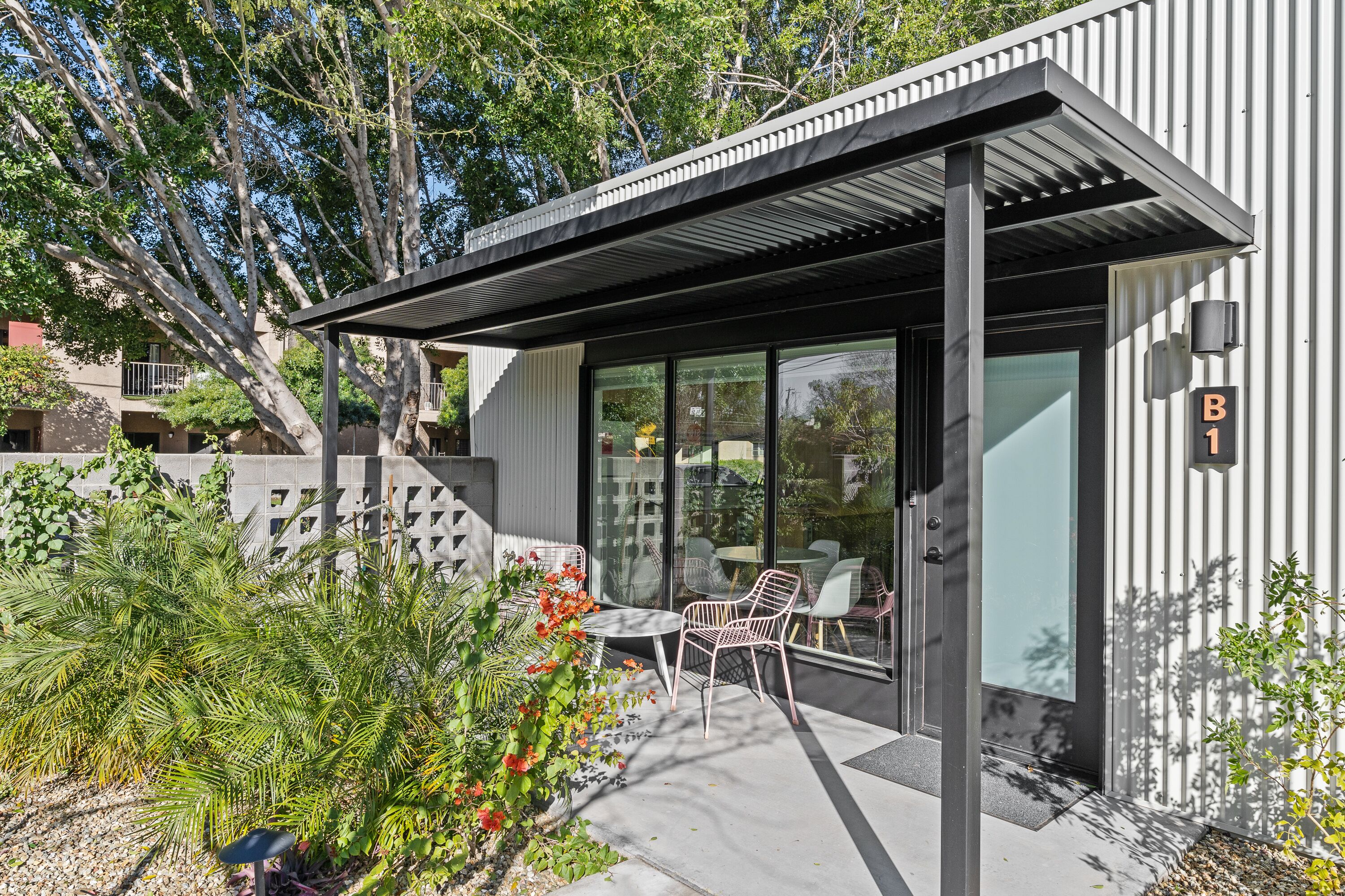 A modern building with a covered patio area featuring outdoor seating.