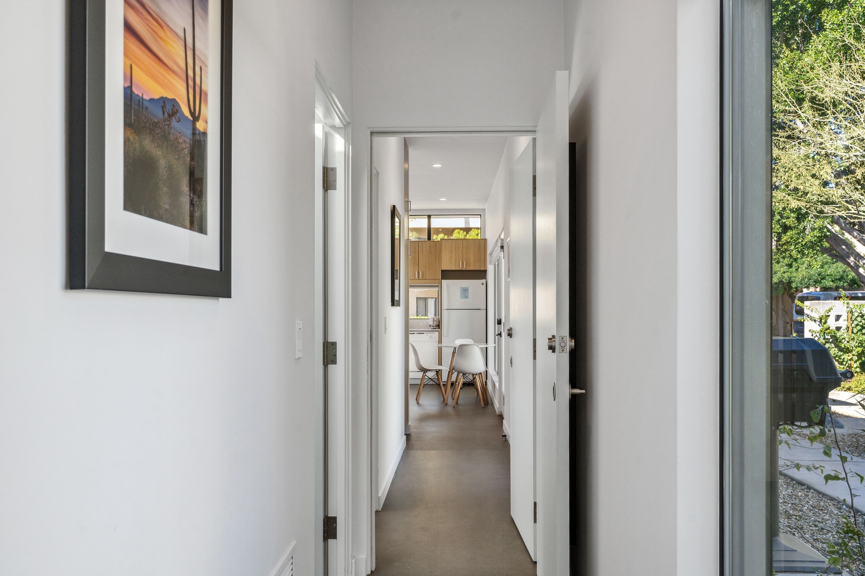A narrow hallway with a dining area at the end, featuring a table and chairs.
