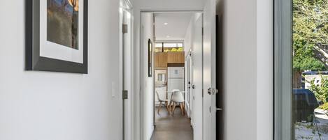A narrow hallway with a dining area at the end, featuring a table and chairs.