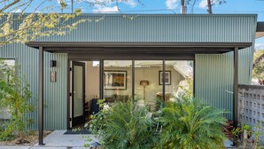 A modern building with a metal exterior, large glass windows, and a covered entrance area with plants. - 4Square Complex (Phoenix)