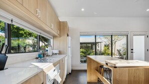 A modern kitchen with wooden cabinets, a large window, and a view of the outdoors. - 4Square Complex (Phoenix)