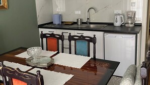 Una cocina pequeña con gabinetes blancos, un lavamanos y una cafetera.