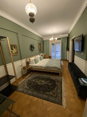 A bedroom with a bed, a bench, a TV, and a view of the outside.
