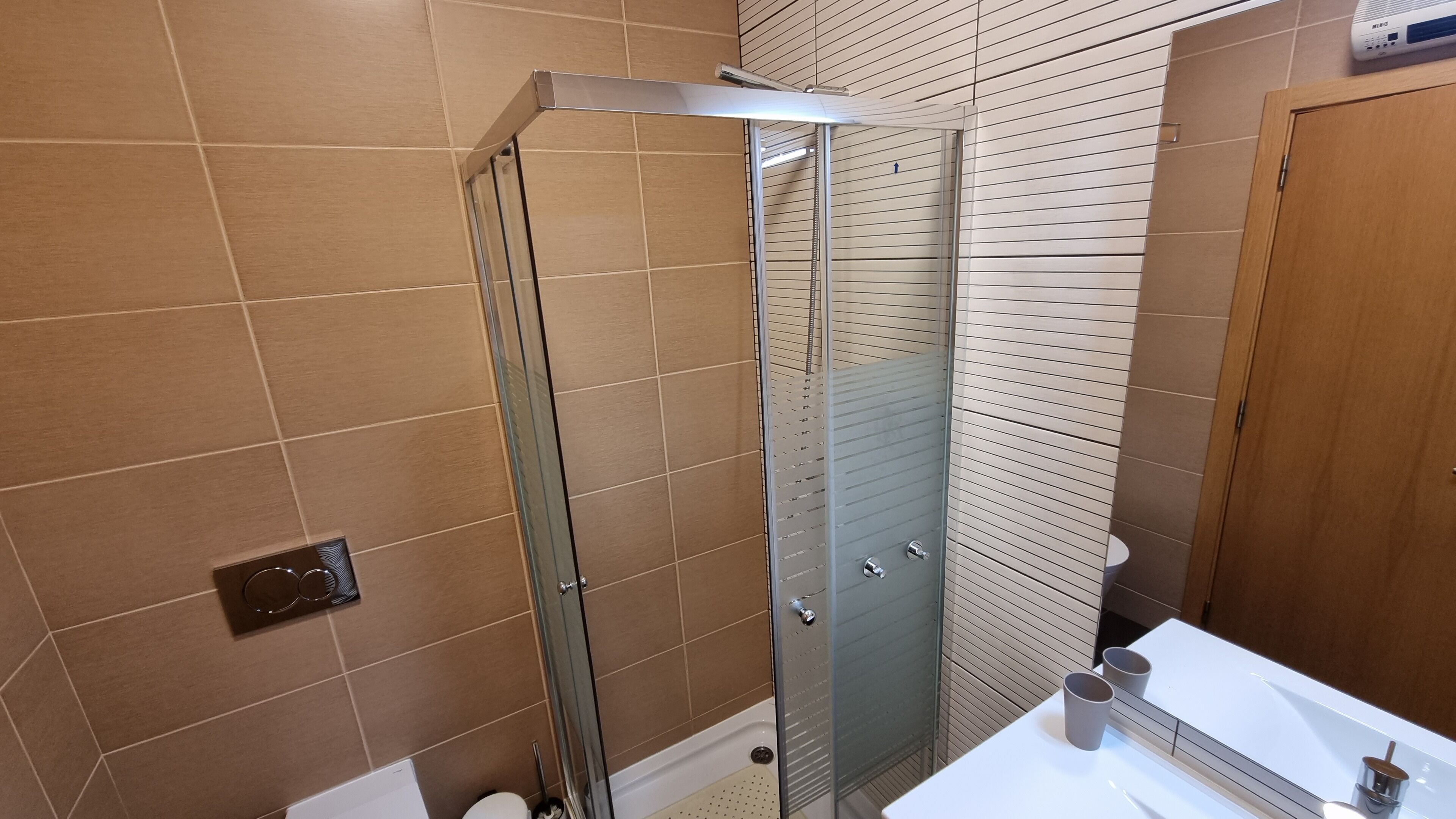 Une salle de bain moderne avec une douche à parois de verre, des toilettes et un lavabo avec un miroir.