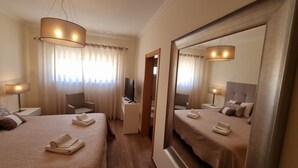 A hotel room with two beds, a television, a chair, and a large mirror.