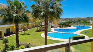 A resort with a large pool, palm trees, and a view of the surrounding landscape.