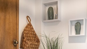 A wooden door with a handle, a woven bag, a potted plant, a small vase, and a hanging net bag. - Escape 2 Nazaré - Private garage in the city (Nazaré)