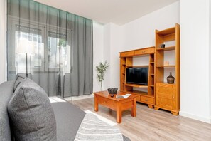 Una sala de estar con sofá, mesa de centro, mueble para televisión y estanterías de madera.