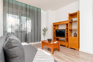Un salon comprenant un canapé, un meuble pour la télévision, un buffet en bois et une petite table.