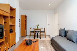 En hyggelig og kompakt bolig med sofa, spisebord med stole, reol og fjernsyn.