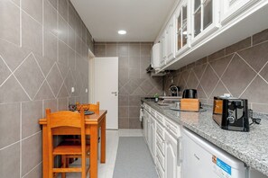 Una cocina compacta con una mesa de comedor, armarios y una cafetera.