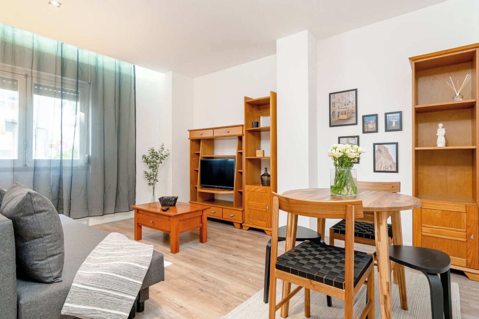Una sala de estar moderna con un sofá, una mesa de centro, un mueble para televisión y un comedor con una mesa y sillas.