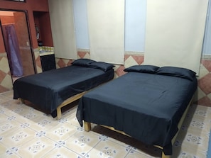 Une chambre avec deux lits simples, une petite table et un haut-parleur.