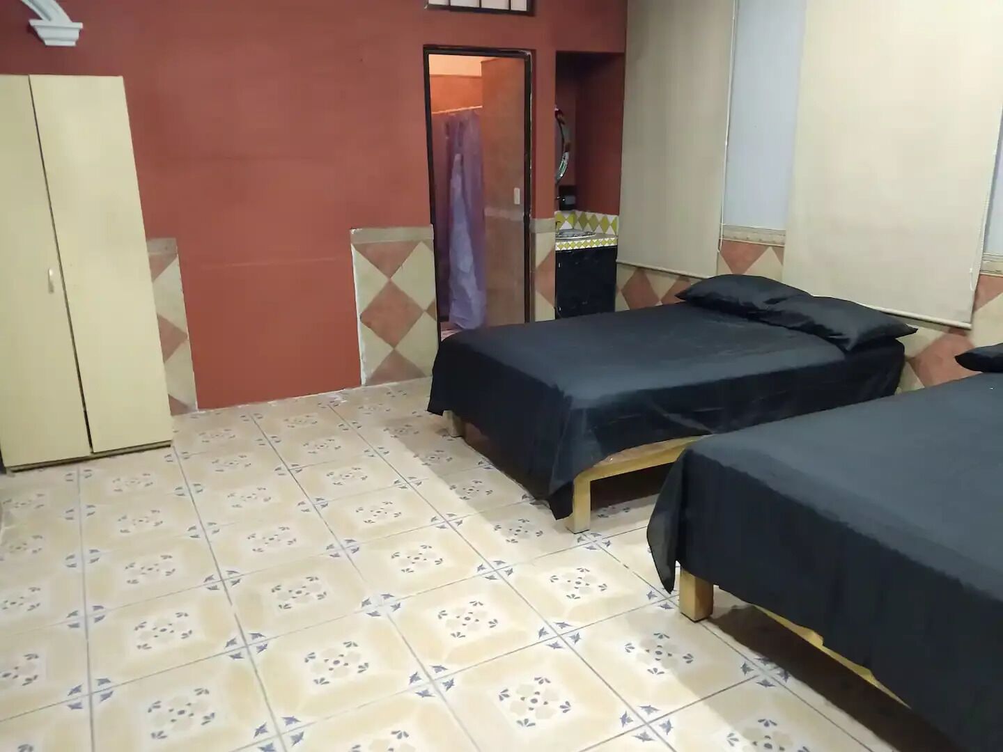 Habitación con dos camas, un armario y un baño visible a través de una puerta abierta.