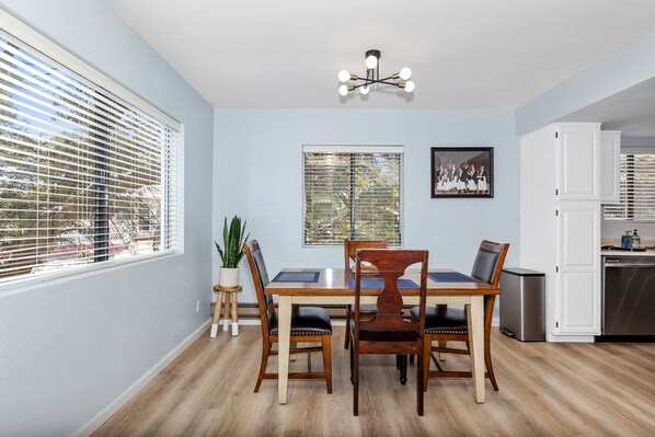 A dining area with a wooden table and chairs, a potted plant, and a chandelier.