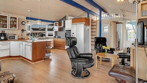 Eine moderne Küche mit Holzschränken, einem Kühlschrank und einer Mikrowelle. Ein Essbereich mit Tisch und Stühlen ist ebenfalls vorhanden.