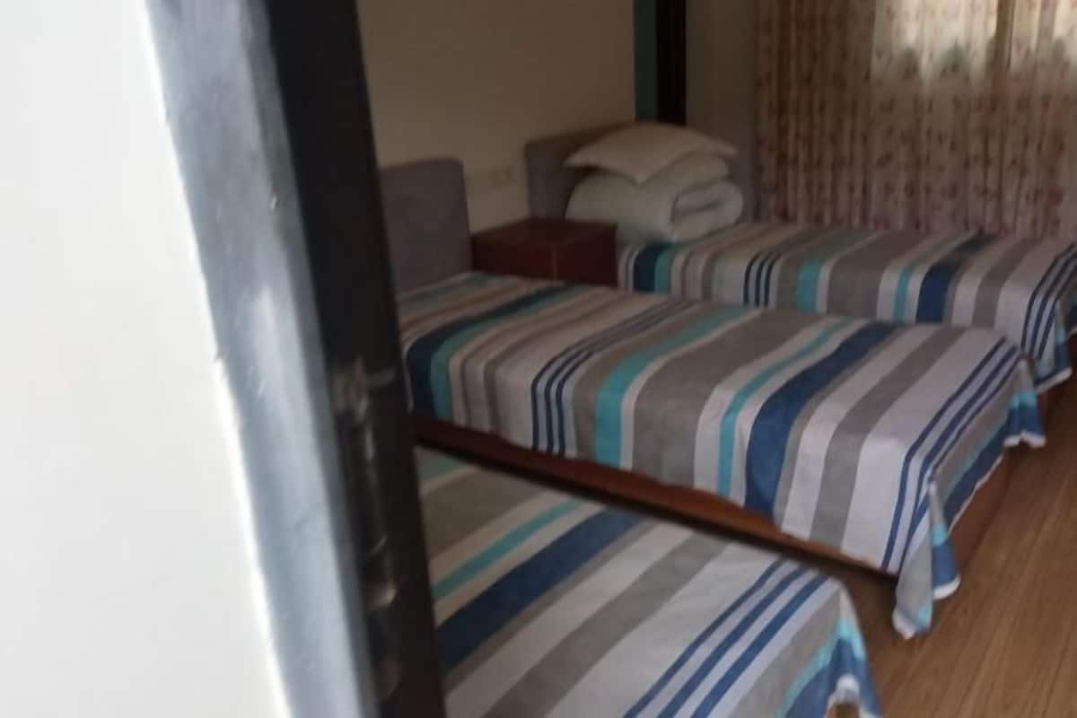 A hotel room with two beds, a nightstand, and a window with curtains.