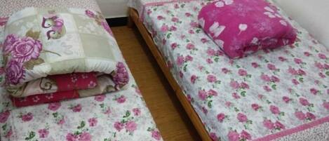 Two single beds with floral bedding and pink pillows.