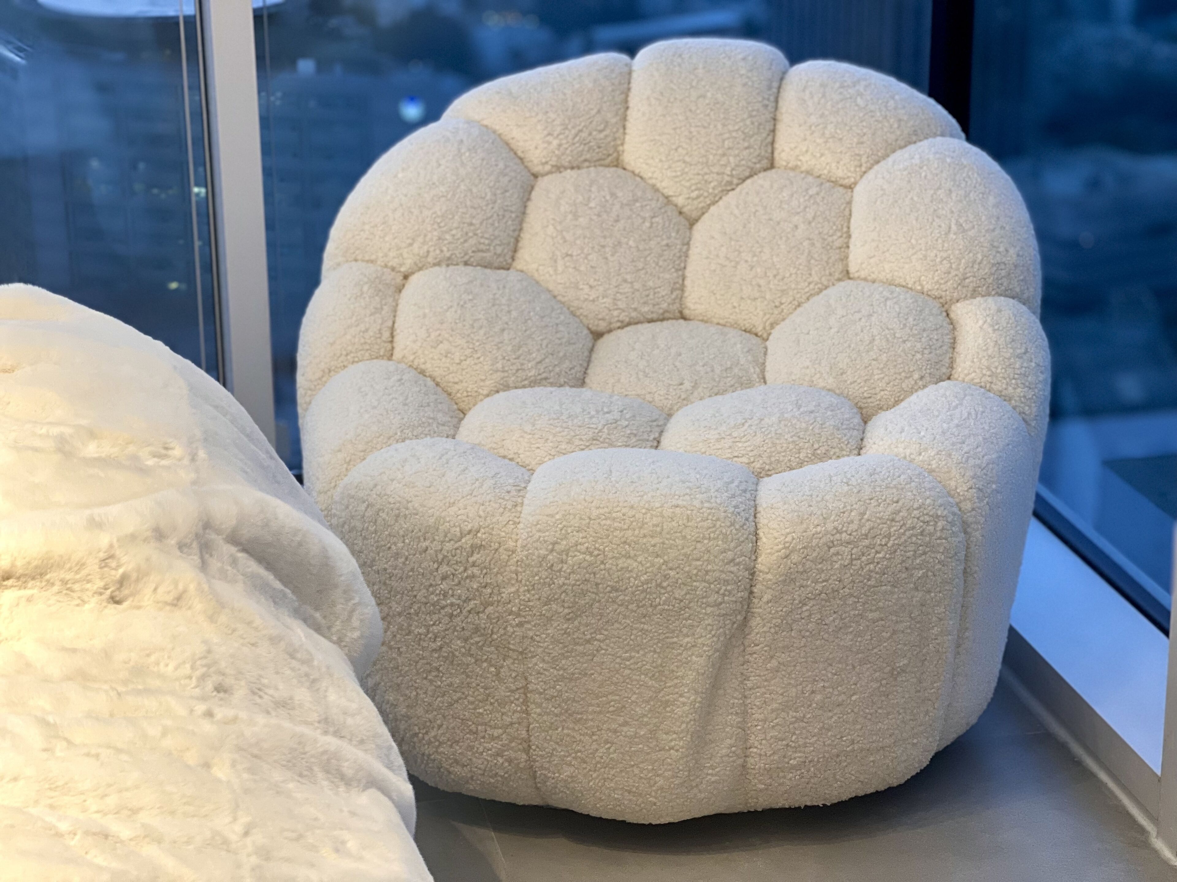 En rund, strukturerad pall med en dekorativ, vågformad kant, placerad på en fönsterbräda.