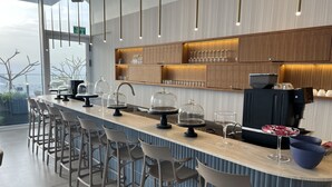 Un espace bar moderne avec un long comptoir, des tabourets de bar et une machine à café.