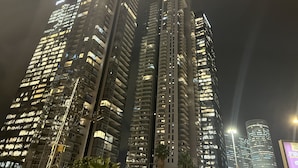 Une vue nocturne d’immeubles de grande hauteur, dont les fenêtres et les balcons sont illuminés, ce qui laisse supposer qu’il s’agit d’une zone urbaine densément peuplée.